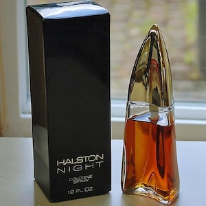 May include: A black rectangular box labeled Halston Night Cologne Spray 1.9 fl oz next to a clear glass perfume bottle with a golden, pointed, conical cap containing an amber-colored liquid, featuring a distinct curved, sculptural glass base design.