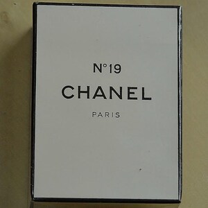 May include: A rectangular box with a white front and gold sides. The front of the box features the text "N&deg;19 CHANEL PARIS" in black, centered on the white background. The box has a black border.