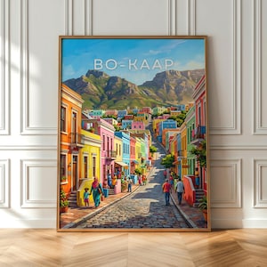 Peut inclure: Une impression encadrée de Bo-Kaap, un quartier coloré du Cap, en Afrique du Sud. L'œuvre représente une rue pavée bordée de maisons vibrantes aux tons orange, jaune, rose et bleu, avec une montagne en arrière-plan et le texte "BO-KAAP".
