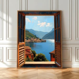 May include: A framed artwork depicts a scenic view through a window with open shutters. The artwork showcases a serene landscape with a lake, mountains, and buildings. The window frame is brown, and the shutters are open, revealing the landscape.