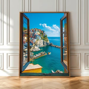 以下が含まれることがあります： 開いた窓から見えるイタリアの海岸沿いの村のシーンを描いた額入りのプリント。 このアートワークは、崖の上のカラフルな建物、ターコイズブルーの水、ふわふわの雲のある明るい青い空を特徴としています。 フレームは温かみのある茶色です。