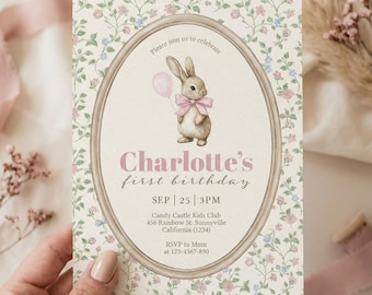 Puede incluir: Una tarjeta de invitación con un diseño floral y un marco ovalado. Dentro del marco hay una ilustración de acuarela de un conejito con un globo rosa. El texto dice "Charlotte's first birthday" con detalles del evento. La tarjeta es sostenida.