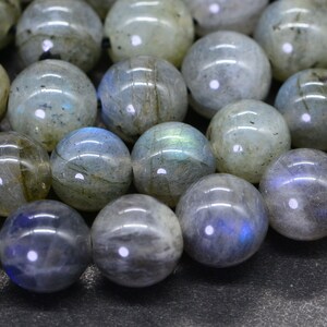 May include: A strand of round, iridescent labradorite beads. The beads are a mix of grey, blue, and green colours with a shimmery, reflective surface.