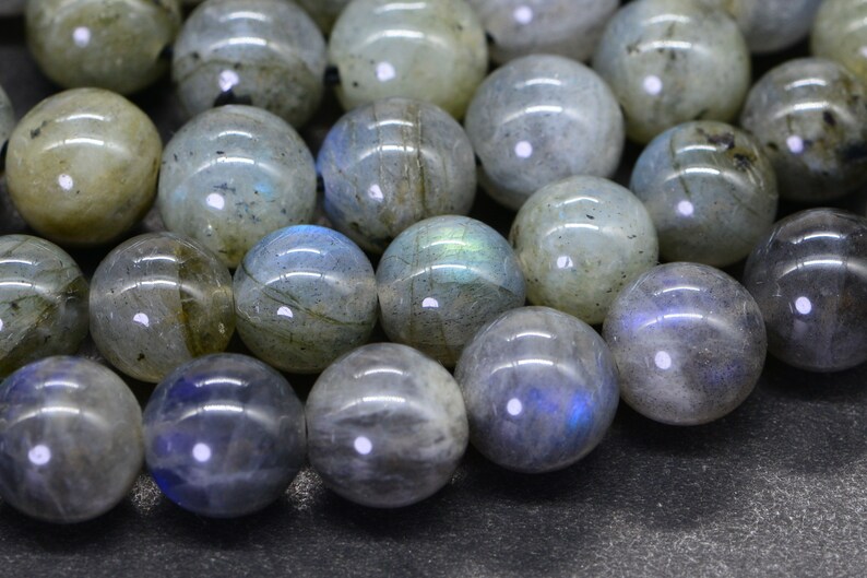 May include: A strand of round, iridescent labradorite beads. The beads are a mix of grey, blue, and green colours with a shimmery, reflective surface.