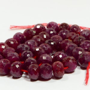 以下が含まれることがあります： 深紅色のルビービーズのストランド。各ビーズはファセットカットされており、丸い形をしています。赤い糸に糸通しされています。