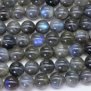 May include: A strand of round, grey labradorite gemstone beads. The beads have a slight iridescent sheen.