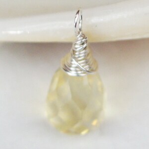 May include: A teardrop-shaped, faceted, light yellow gemstone pendant with a silver wire wrap.