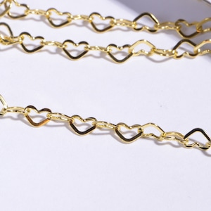 May include: A gold heart-shaped chain necklace. The chain is made of small, interconnected heart-shaped links.