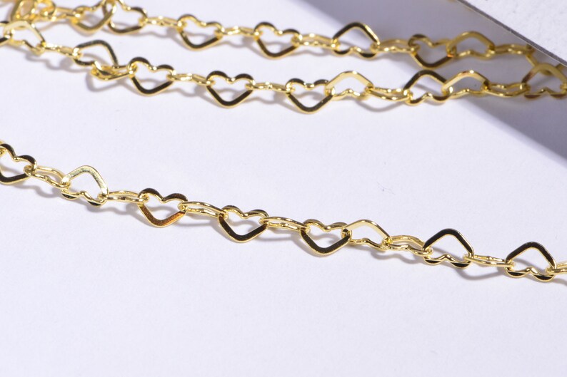 May include: A gold heart-shaped chain necklace. The chain is made of small, interconnected heart-shaped links.