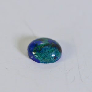 May include: A round, blue and green gemstone cabochon with a smooth, polished surface.