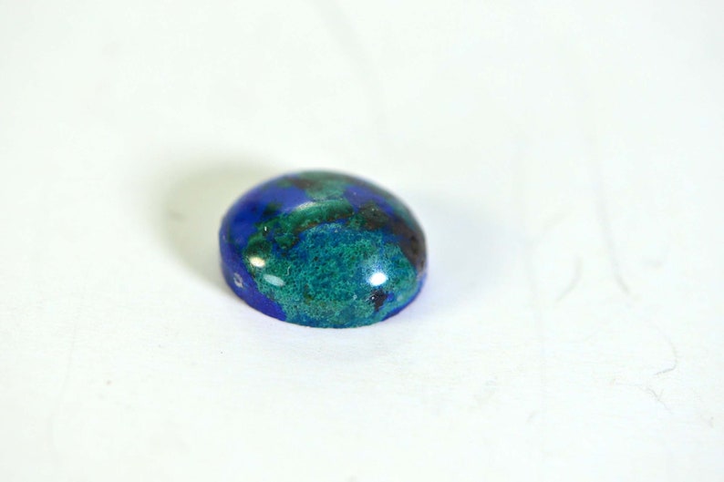 May include: A blue and green oval cabochon gemstone with a smooth, polished surface.