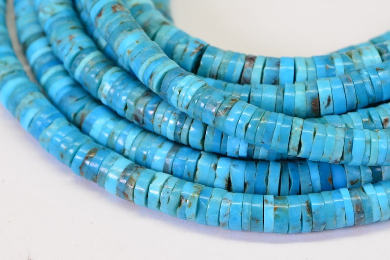 May include: A strand of turquoise beads, each bead is a flat, round disc with a light blue color and brown markings.