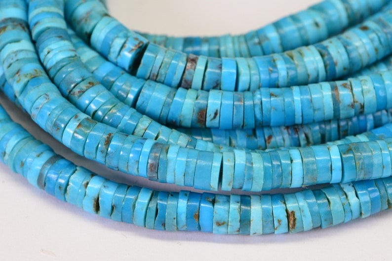 May include: A strand of turquoise beads, each bead is a flat, round disc with a light blue color and brown markings.
