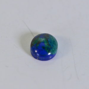 May include: Oval-shaped gemstone with a blue and green color pattern. The gemstone has a smooth, polished surface.