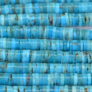 May include: A strand of turquoise beads, each bead is a flat, rectangular shape with rounded edges. The beads are a vibrant blue color with brown and white marbling.