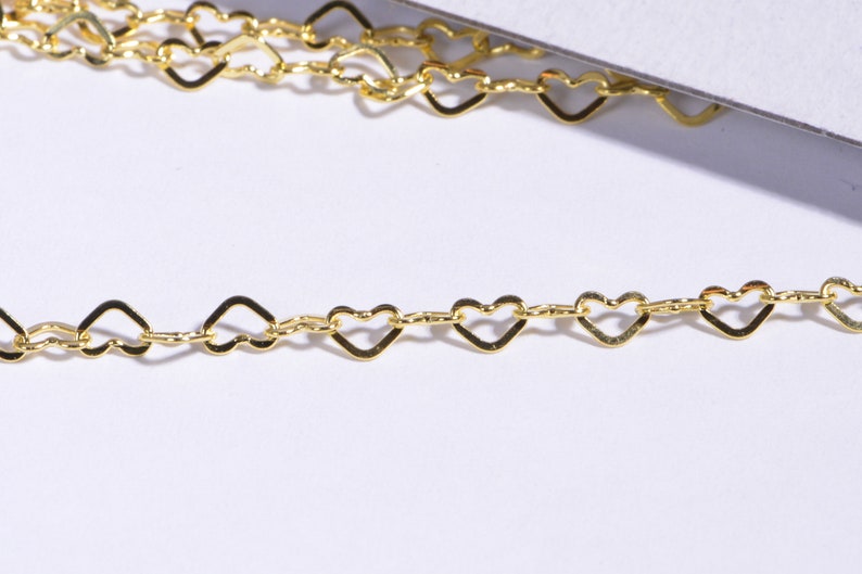 May include: A gold heart-shaped chain necklace. The chain is made of small, delicate hearts linked together.
