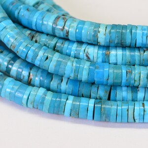 May include: A strand of turquoise beads, each bead is a flat, round disc with a light blue color. The beads are stacked on top of each other, creating a layered effect.