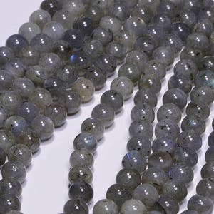 May include: A strand of grey labradorite gemstone beads. The beads are round and have a smooth, polished finish. The labradorite has a subtle iridescent sheen.