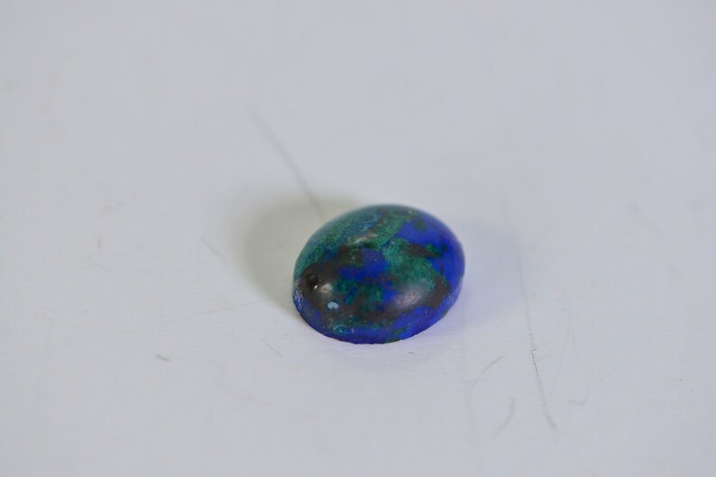 May include: Oval shaped blue and green gemstone cabochon.