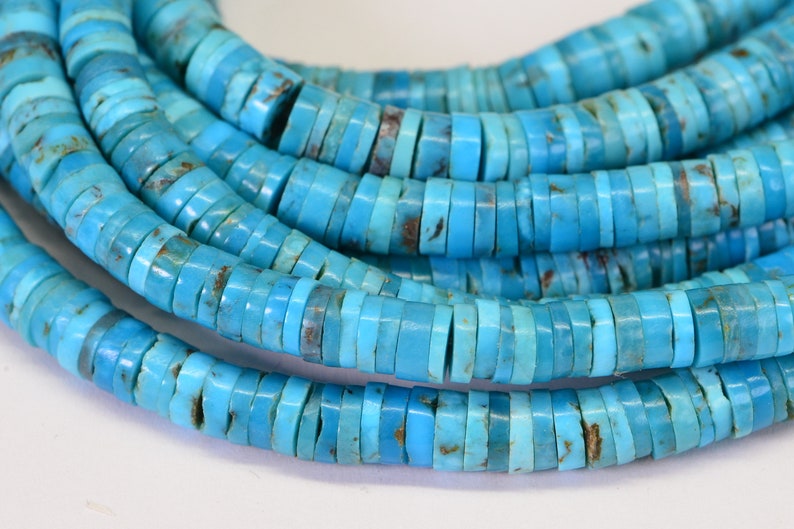 May include: A strand of turquoise beads, each bead is a flat, round disc with a light blue color and a slightly irregular shape.