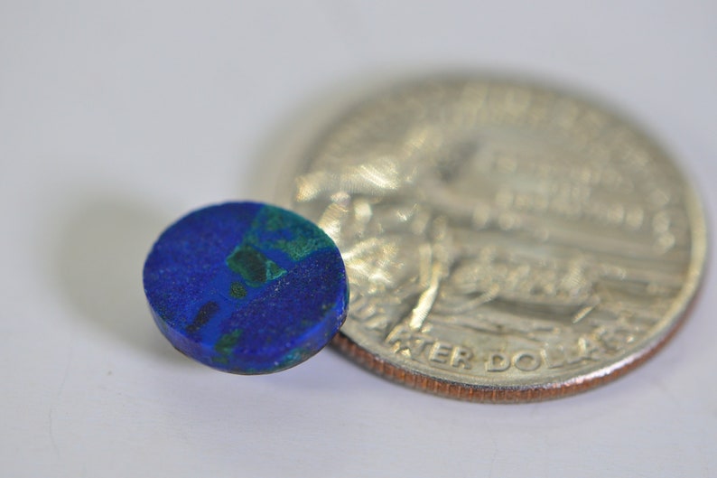 May include: A small, round, blue and green gemstone cabochon, about the size of a US quarter.