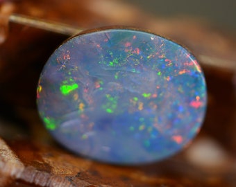May include: A close-up of a round, light blue opal gemstone with iridescent flashes of green, red, and blue.