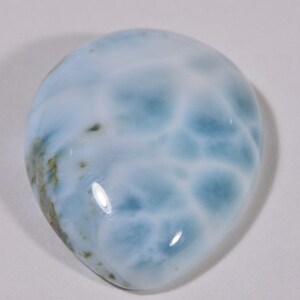 May include: A teardrop-shaped cabochon of blue and white ocean jasper with a smooth, polished surface.
