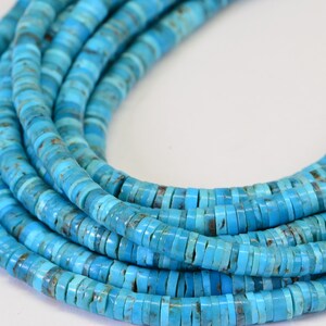 May include: A strand of turquoise beads, each bead is a flat, round disc with a light blue color and a slightly mottled pattern.