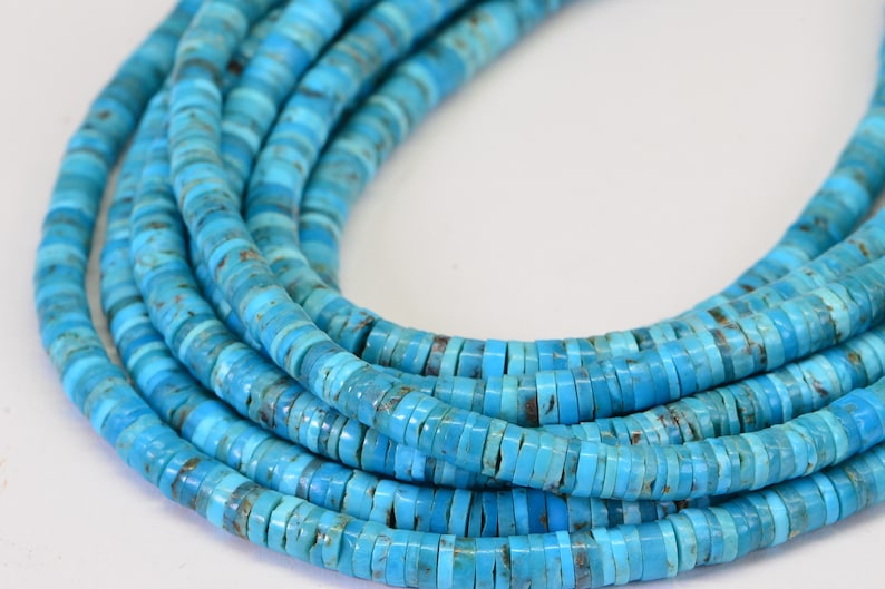 May include: A strand of turquoise beads, each bead is a flat, round disc with a light blue color and a slightly mottled pattern.