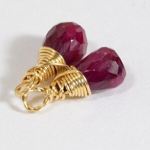 May include: Two ruby red gemstone earrings with gold wire wrapping.