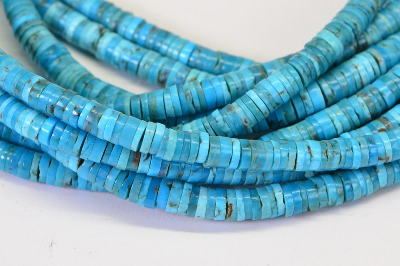 May include: A strand of turquoise beads, each bead is a flat, round disc with a light blue color. The beads are stacked on top of each other, creating a layered effect.