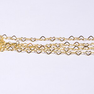 May include: A gold heart-shaped chain necklace. The chain is made of small, delicate hearts linked together.