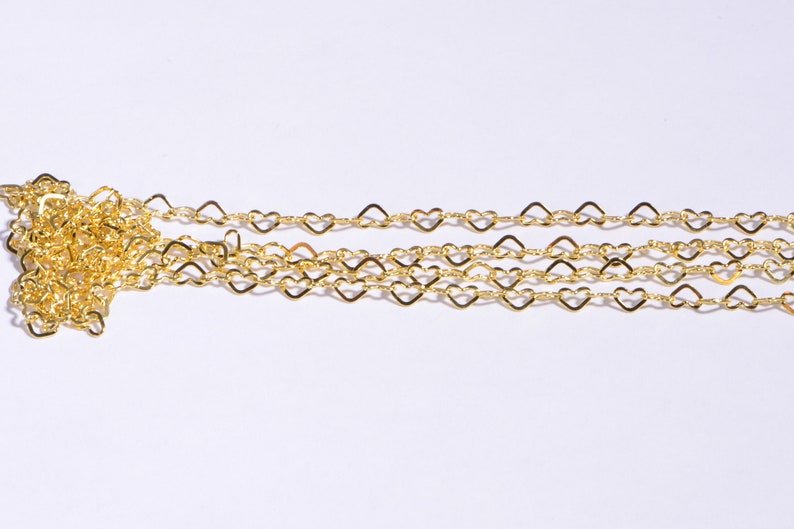 May include: A gold heart-shaped chain necklace. The chain is made of small, delicate hearts linked together.