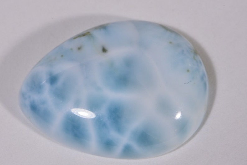 May include: A smooth, light blue and white, oval-shaped, polished gemstone with a cloudy, marbled pattern.