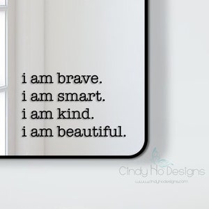 Op de afbeelding: Een zwarte spiegel met een witte achtergrond en de tekst "i am brave. i am smart. i am kind. i am beautiful." gedrukt op de spiegel.