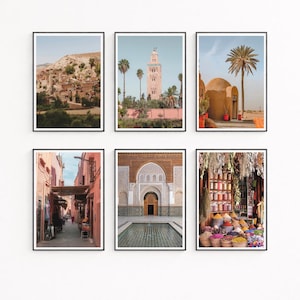 May include: A set of six framed wall art prints featuring Moroccan scenes: a hillside village, a tall minaret, a desert palm tree, a narrow pink alleyway, an ornate courtyard with a reflecting pool, and a vibrant spice market stall with colorful goods.