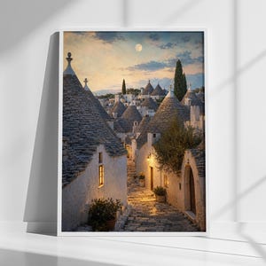 Puede incluir: Una impresión artística enmarcada que representa una calle estrecha de adoquines bordeada por casas trulli de piedra blanca con techos cónicos grises. La escena ocurre al atardecer bajo una luna pálida, con luz dorada cálida desde ventanas y faroles.
