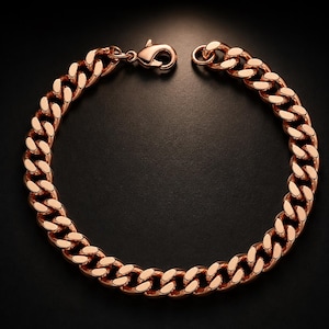 Op de afbeelding: Een roségouden gourmetarmband. De armband heeft een reeks in elkaar grijpende ovale schakels, waardoor een gedurfd ontwerp ontstaat. De sluiting is in bijpassend roségoud en de armband wordt tegen een donkere achtergrond gepresenteerd.