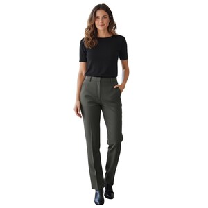 May include: A woman wearing a black short-sleeve top and dark green dress pants. The pants have a straight leg design. The woman is wearing black ankle boots. The background is white.