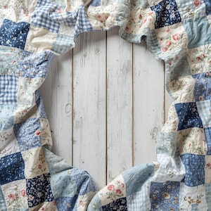 May include: A patchwork quilt with a variety of blue and white patterns, including floral, gingham, and solid squares, is draped over a white wooden surface. The quilt's edges frame an open space, creating a visual border.