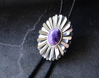 May include: A silver bolo tie with a purple gemstone set in a daisy-shaped design.