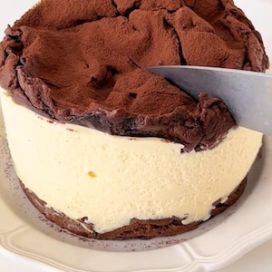 Pode incluir: Uma caneca de cerâmica branca com uma alça preta e o texto "But First, Coffee" em preto, em negrito. A caneca está sobre uma superfície branca.