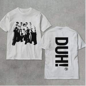 Puede incluir: Camisetas blancas con un gráfico en blanco y negro de un grupo de personas. Una camiseta muestra la imagen del grupo, la otra tiene la palabra "DUH!" impresa verticalmente en negro en la espalda.