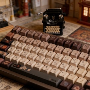 May include: A mechanical keyboard featuring a brown and cream color scheme with QWERTY layout keys, including specialized icons on the modifier keys. A miniature black typewriter model sits behind the keyboard, which is placed on a patterned surface.