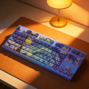 May include: A mechanical keyboard featuring a light blue frame and keycaps printed with a swirling blue, yellow, and white oil painting pattern. The keys are backlit with a thin strip of multicolored LED lighting visible between the keycaps.
