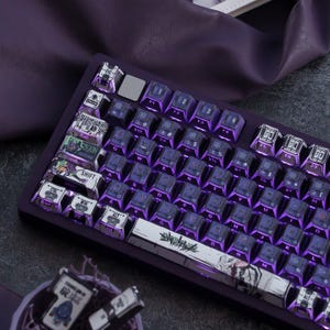 Puede incluir: Un teclado mecánico con un marco de color morado intenso y teclas retroiluminadas. Las teclas presentan una mezcla de superficies moradas oscuras con detalles en blanco, incluyendo gráficos personalizados y texto como ESC, SHIFT y ALT. La barra espaciadora muestra una ilustración detallada.