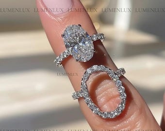 May include: Two silver-toned rings featuring clear, sparkling stones. The top ring has a large oval-cut centre stone, while the bottom ring is an oval-shaped band encrusted with small pavé stones. Both rings have thin bands with small stones.