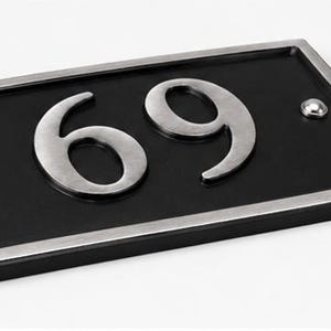 Puede incluir: Placa rectangular negra con el n&uacute;mero 69 en plata. La placa tiene un borde plateado y dos remaches plateados. Un dise&ntilde;o moderno y elegante para mostrar el n&uacute;mero de la casa.