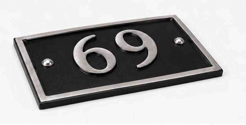 Puede incluir: Placa rectangular negra con el n&uacute;mero 69 en plata. La placa tiene un borde plateado y dos remaches plateados. Un dise&ntilde;o moderno y elegante para mostrar el n&uacute;mero de la casa.