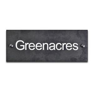 May include: A rectangular, dark grey slate house sign. The name "Greenacres" is displayed in a white, sans-serif font. The sign is fixed with two silver screws, one on each side.